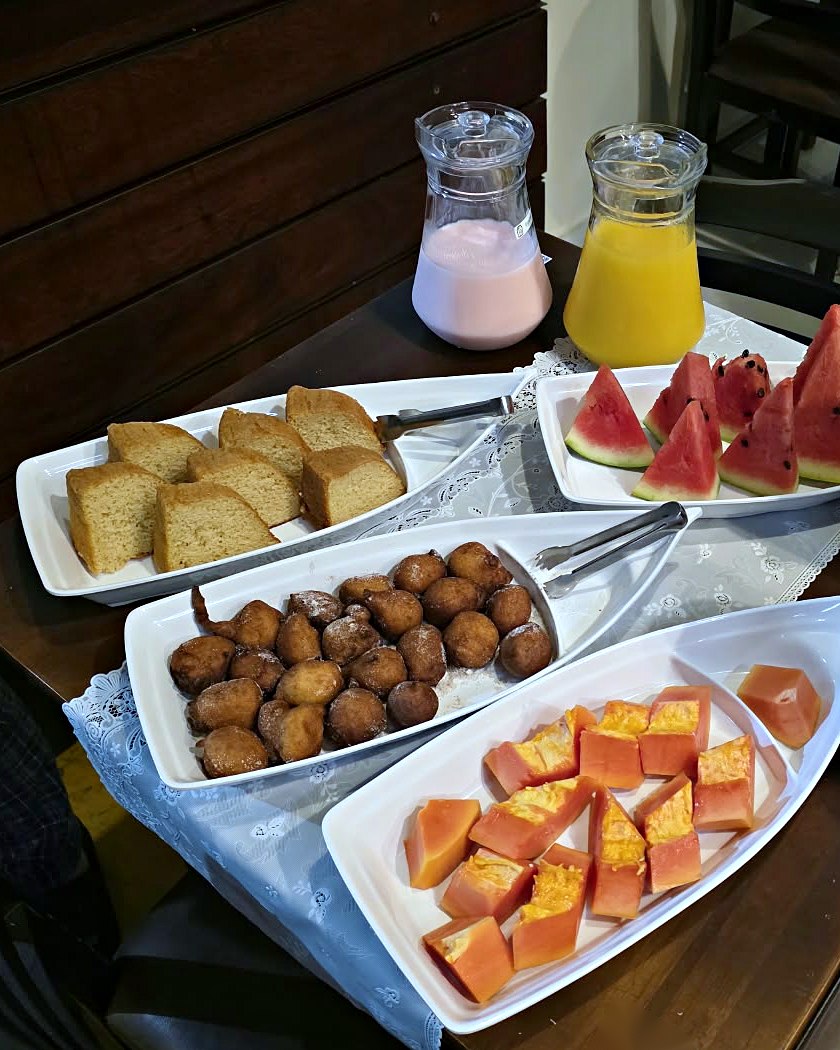 Café da manhã com frutas, bolo, bolinho de chuva, suco e iogurte