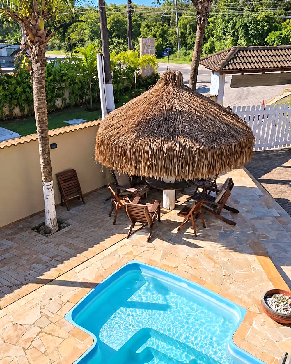 Piscina, deck de pedra e quiosque de sapê da pousada